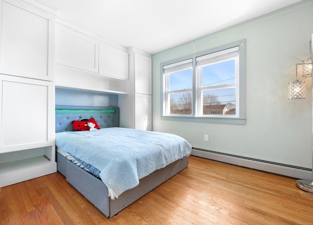 bedroom with a baseboard heating unit and light wood-style flooring