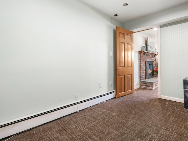 unfurnished room with dark colored carpet, baseboards, a fireplace, and baseboard heating