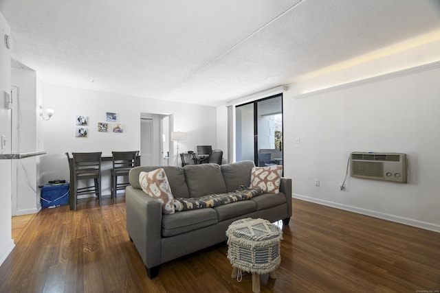 living area with a textured ceiling, a wall unit AC, wood finished floors, and baseboards