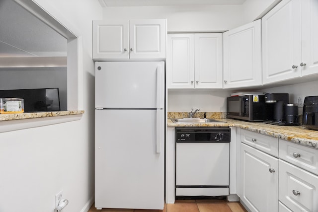 kitchen with white appliances, a sink, light stone countertops, and white cabinets