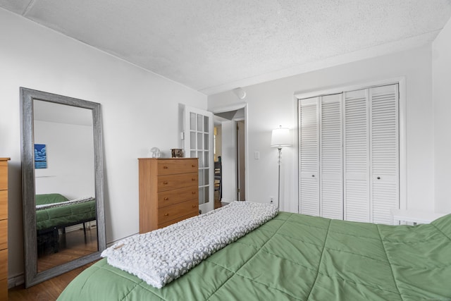 bedroom with a textured ceiling, dark wood finished floors, and a closet