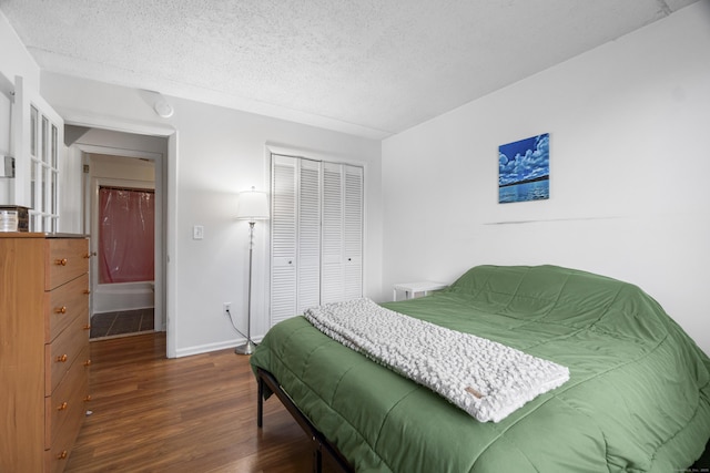 bedroom with dark wood-style floors, a closet, a textured ceiling, and baseboards