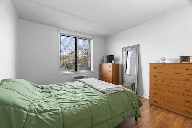 bedroom featuring an AC wall unit and wood finished floors