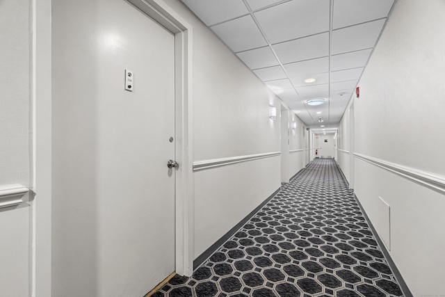 corridor with a paneled ceiling and tile patterned floors