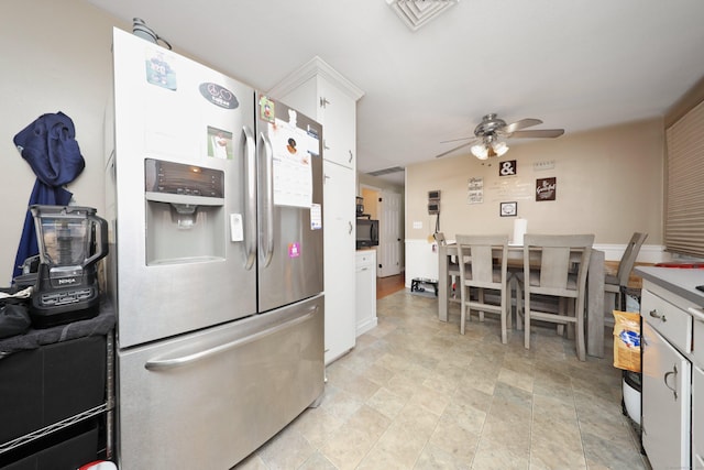 kitchen with a ceiling fan, white cabinets, stainless steel fridge, and visible vents