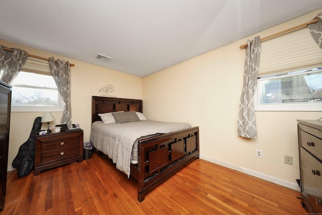 bedroom featuring visible vents, baseboards, and wood finished floors