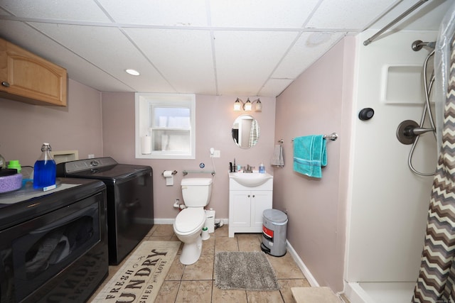 bathroom featuring toilet, a shower with shower curtain, a drop ceiling, independent washer and dryer, and baseboards