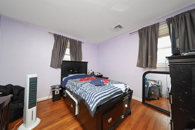 bedroom with visible vents, baseboards, and wood finished floors