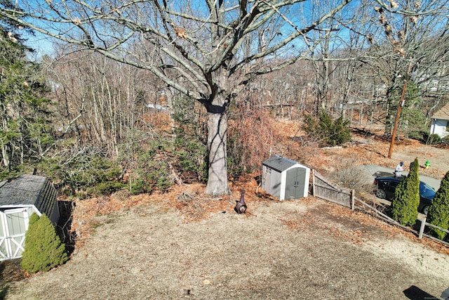 view of yard with a storage shed, an outbuilding, and fence