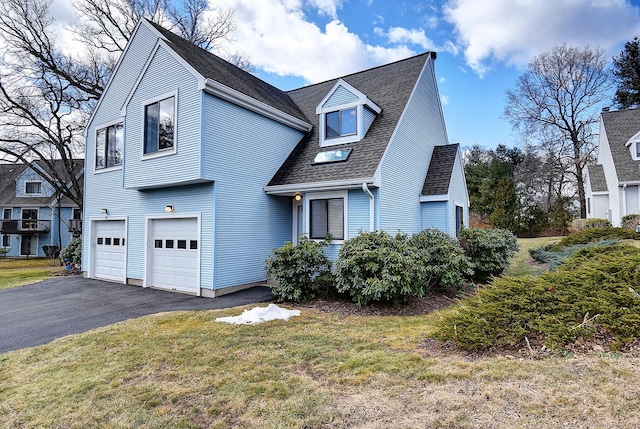 view of front of home featuring an attached garage, driveway, a front lawn, and a shingled roof