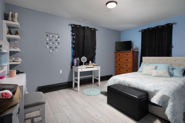 bedroom with light wood finished floors and baseboards