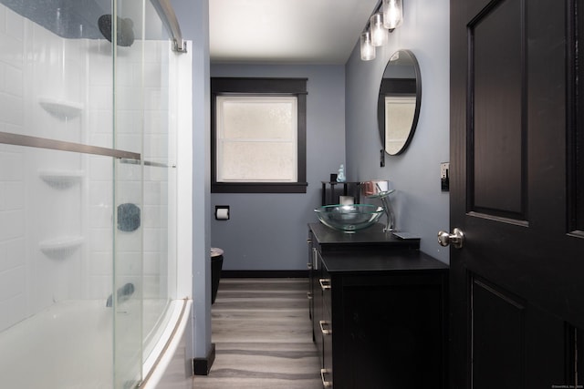 full bathroom featuring enclosed tub / shower combo, vanity, baseboards, and wood finished floors