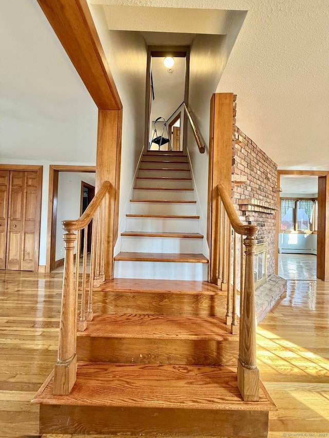 stairs featuring a textured ceiling and wood finished floors