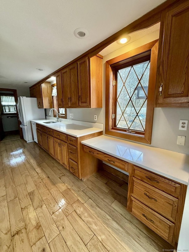 kitchen featuring light wood-type flooring, brown cabinets, and a sink