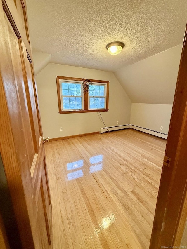 bonus room with light wood-type flooring, baseboards, a textured ceiling, and lofted ceiling