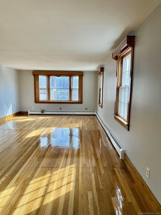 unfurnished living room featuring a baseboard heating unit, a textured ceiling, and hardwood / wood-style floors