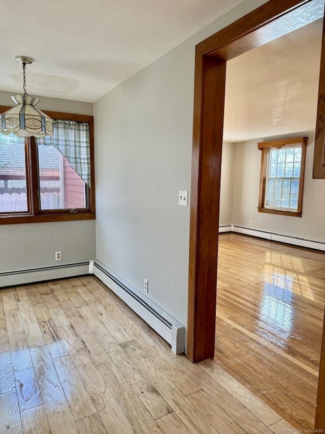 spare room featuring a baseboard heating unit, a textured ceiling, and wood-type flooring