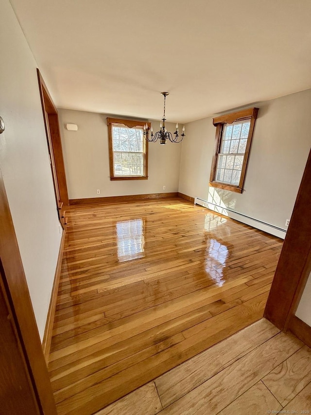 unfurnished dining area with a baseboard heating unit, light wood-type flooring, a wealth of natural light, and a notable chandelier