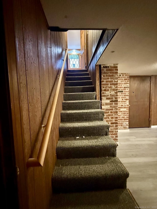 staircase featuring wood walls and wood finished floors