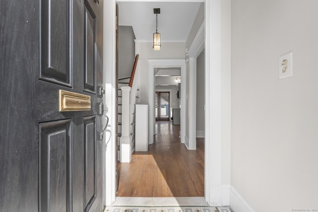 foyer entrance featuring dark wood-style floors, stairs, baseboards, and crown molding