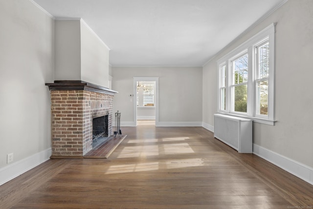 unfurnished living room with baseboards, radiator heating unit, ornamental molding, wood finished floors, and a brick fireplace