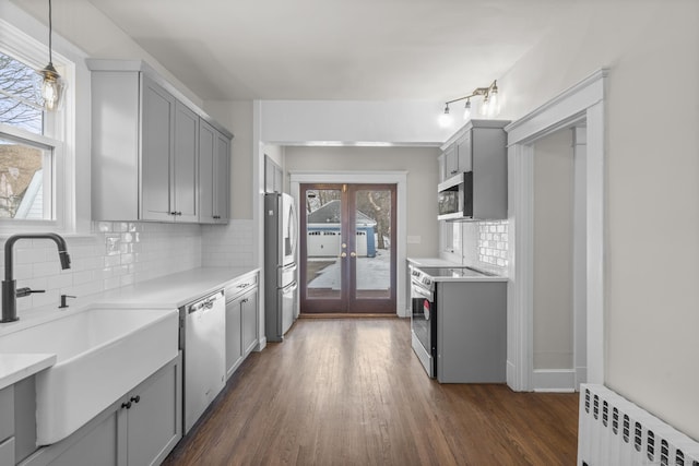 kitchen with stainless steel appliances, radiator, light countertops, gray cabinets, and a sink