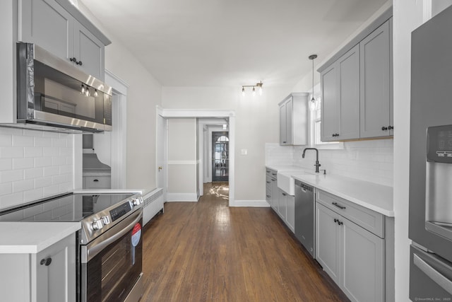 kitchen with decorative light fixtures, light countertops, gray cabinetry, appliances with stainless steel finishes, and a sink