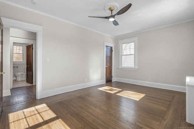 spare room with dark wood-style floors, plenty of natural light, baseboards, and ornamental molding