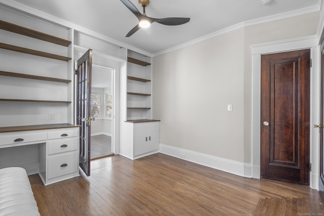 unfurnished bedroom featuring baseboards, ornamental molding, dark wood-type flooring, and built in study area