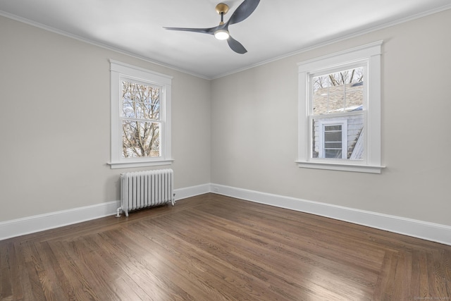 empty room featuring dark wood-style floors, baseboards, a healthy amount of sunlight, and radiator heating unit