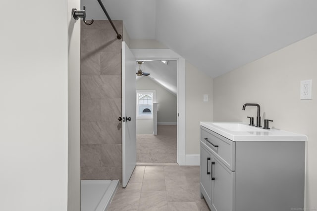 full bathroom featuring baseboards, lofted ceiling, ceiling fan, a tile shower, and vanity