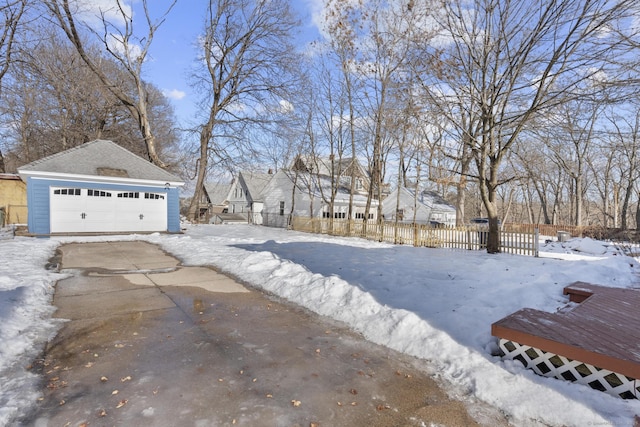 yard layered in snow with a garage, an outdoor structure, and fence