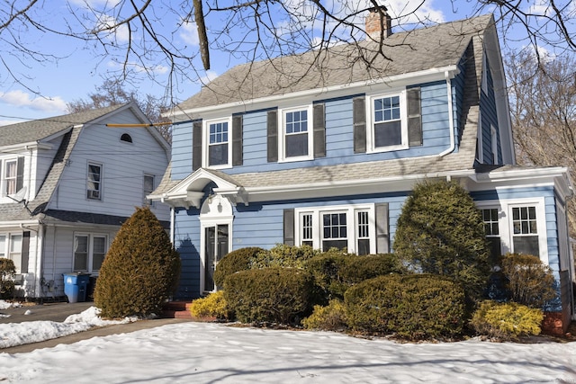 view of front of property with a shingled roof, a chimney, and a gambrel roof