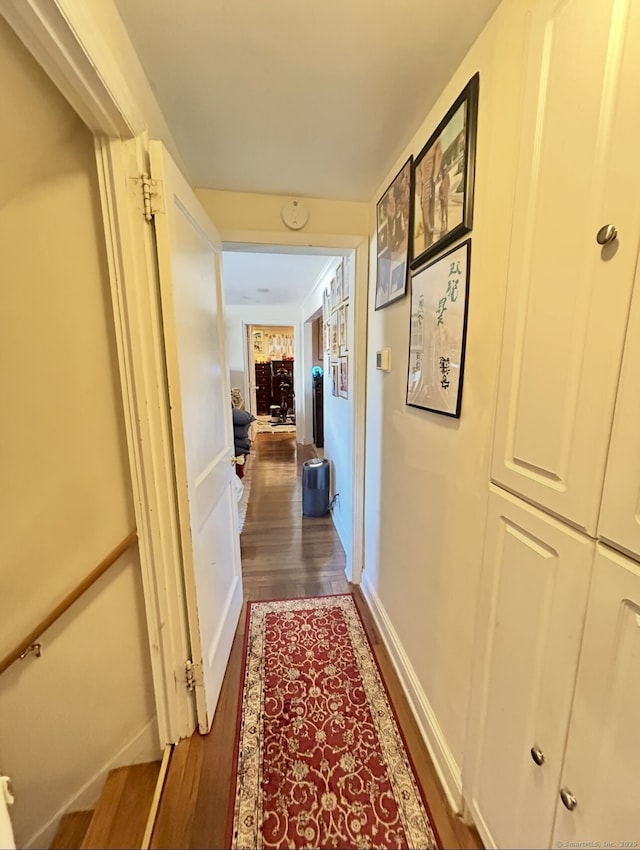 hallway featuring baseboards and dark wood finished floors