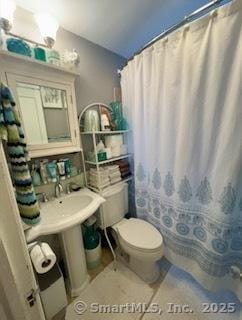 bathroom with a shower with shower curtain and toilet