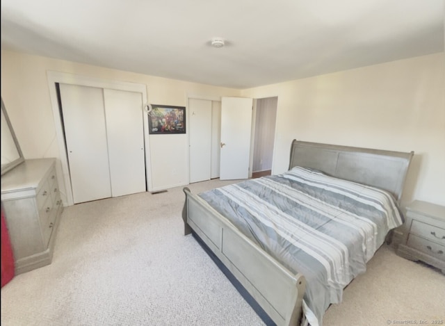 bedroom with light carpet and two closets