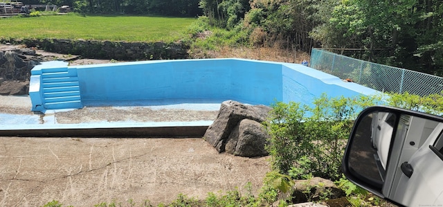 view of swimming pool featuring fence and a yard