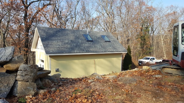 view of side of property with a shingled roof and an outdoor structure