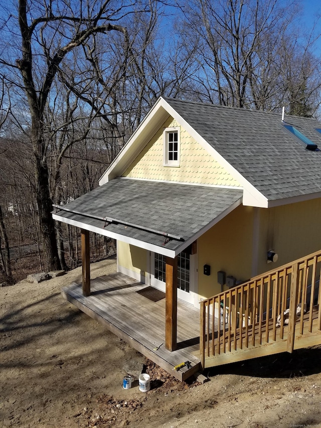 view of home's exterior featuring a shingled roof and a wooden deck