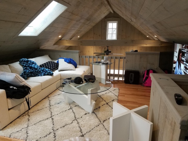 interior space with lofted ceiling with skylight, wooden walls, and wood finished floors