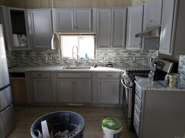 kitchen with under cabinet range hood, stainless steel appliances, a sink, visible vents, and tasteful backsplash