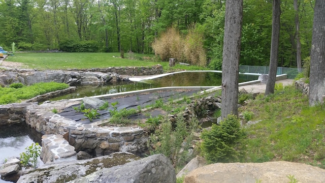 view of home's community featuring a lawn, fence, and a view of trees