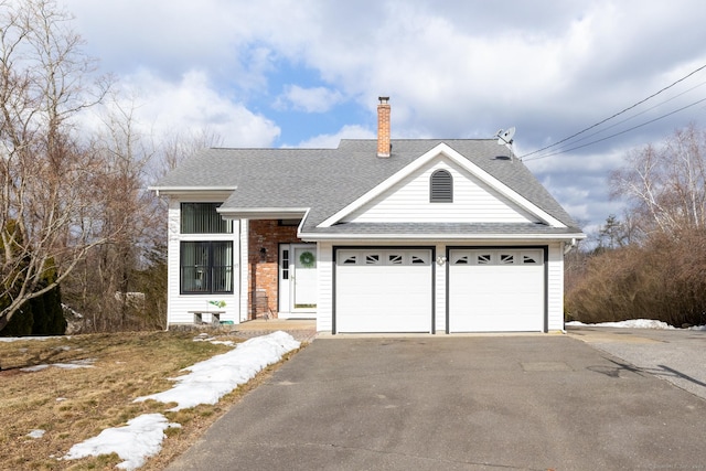 view of front of property featuring a shingled roof, a chimney, an attached garage, and aphalt driveway