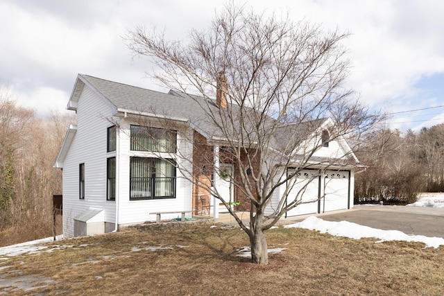 view of front of home featuring a garage, aphalt driveway, and roof with shingles