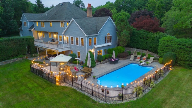 rear view of property featuring a fire pit, an outdoor kitchen, a lawn, a chimney, and a patio area