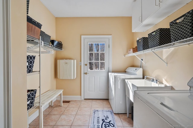 laundry room featuring baseboards, cabinet space, washing machine and clothes dryer, and light tile patterned floors