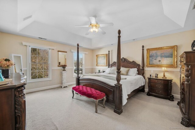 bedroom featuring a tray ceiling, light carpet, and visible vents