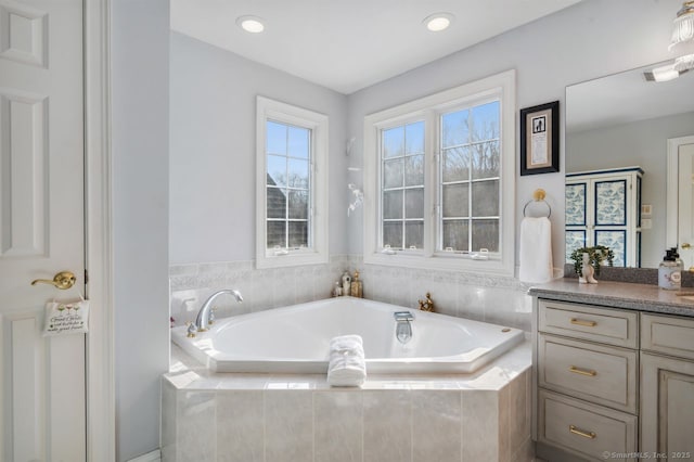 bathroom with a garden tub, vanity, and recessed lighting