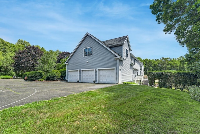 view of home's exterior with a yard, an attached garage, and driveway