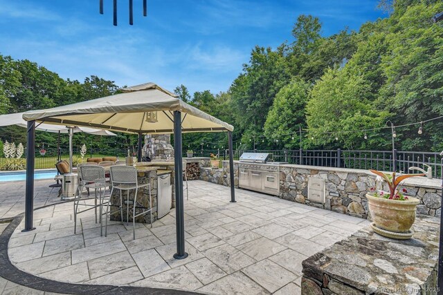 view of patio / terrace with a gazebo, fence private yard, outdoor dry bar, and area for grilling